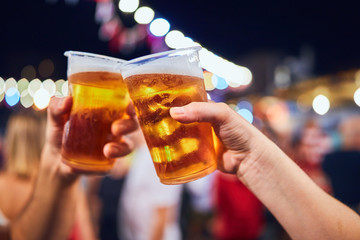 Friends drinking beer at night with de-focused lights in the background. Shallow focus.