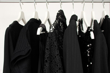 set of women's clothing in black in different colors on hangers, a concept for fashion, mourning...