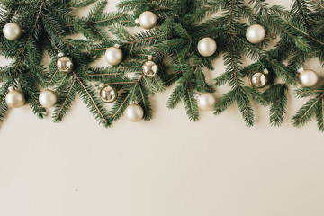 Christmas / New Year holiday composition. Hero header with blank copy space, fir needle branches, Christmas baubles on beige background. Flat lay, top view festive concept.
