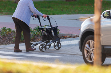 Alte Frau mit Rollator überquert eine Strasse