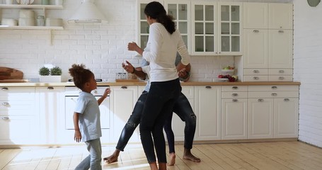 Carefree happy active african family of four dancing at home