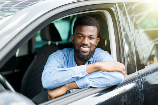 Closeup portrait happy smiling young african man sitting in his new car excited ready for trip