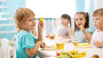 children eating healthy food in kindergarten or daycare