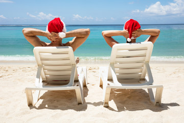 Young Couple Sitting On Deck Chair At Beach