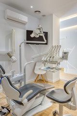 Fully equipped modern dental clinic box, with white walls and wooden floor. Dental radiography shown on monitor.