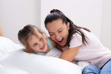 Mother And Her Daughter Hugging On Bed