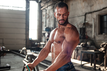 Fototapeta premium Muscled half naked man at work in an old factory.