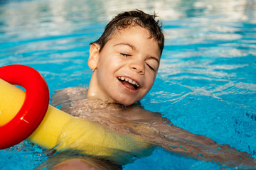 niño jugando y riendo en terapia en piscina con tubo flotador