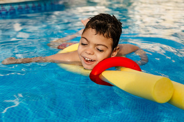 niño jugando y riendo en terapia en piscina con tubo flotador