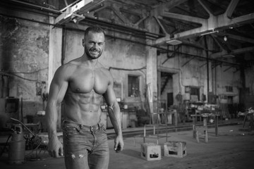 Muscled half naked man at work in an old factory.