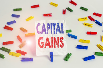 Text sign showing Capital Gains. Business photo showcasing Bonds Shares Stocks Profit Income Tax Investment Funds Colored clothespin papers empty reminder white floor background office