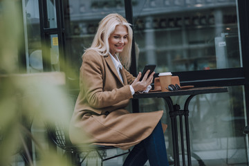 Happy woman is looking on smartphone screen