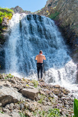 Obraz premium A man stands on the background of a waterfall