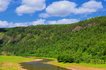 Fototapeta na wymiar A small river with a slow current, landscape with beautiful blue sky. Mountain river and forest with sky and clouds.
