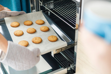 Woman is taking baking tray with baking