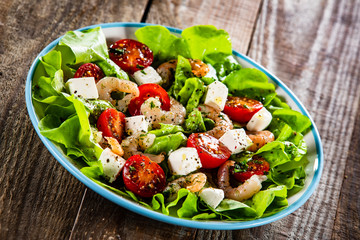 Salad with shrimps and feta cheese on wooden table