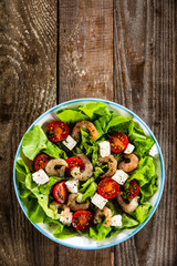 Salad with shrimps and feta cheese on wooden table