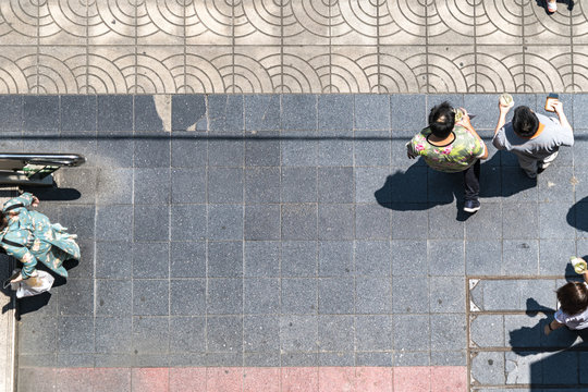 Top View Of Crowd People Walk On Pedestrian Concrete Grey Block Street  Pavement. Concept Aerial View Pedestrian Space.