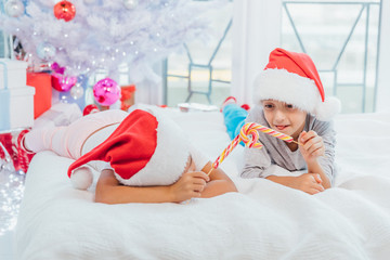 Warm Christmas atmosphere in which joyful sister and brother playing with candy canes, imitating a...