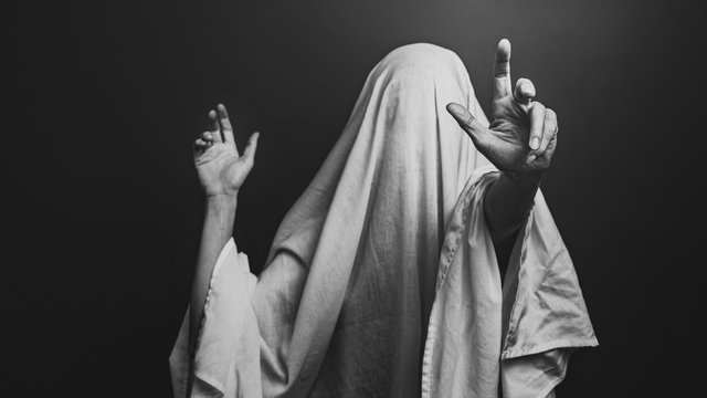 Spooky white ghost on a gray background, black and white image. Halloween horror minimal concept