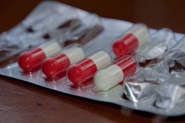 Medication capsules in macro view and dark brown background