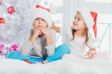 Loving sister is comforting her upset brother, patting his head, smiling.