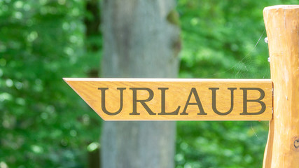 Holzschild mit Text URLAUB im Park bei Sonnenschein