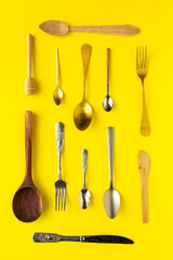 Spoons and forks on yellow background