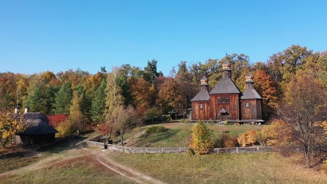 Wooden orthodox church in the village. Paints of golden autumn. Aerial view.