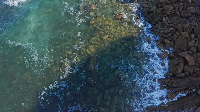 Ascending shot over sea waves breaking in the reefs and coast, Cantabrian sea, Spain - drone aerial view