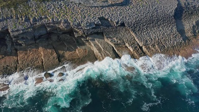 Descending shot over sea waves breaking in the reefs and coast, Cantabrian sea, Spain - drone aerial view