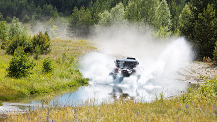  ATV vehicle boosts water hurdle surrounded by splashes.