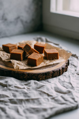 Fresh caramel fudge candies on a wooden plate with copy space in marble background
