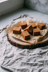 Fresh caramel fudge candies on a wooden plate with copy space in marble background