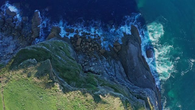 Ascending shot over sea waves breaking in the reefs and coast, Cantabrian sea, Spain - drone aerial view