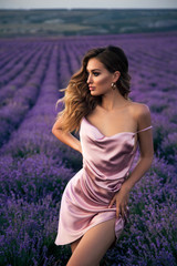 beautiful girl with blond hair in elegant clothes posing in summer flowering lavender field
