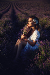 beautiful girl with blond hair in elegant clothes posing in summer flowering lavender field