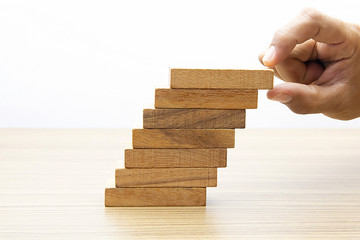 Businessman hand is placing the wooden pieces carefully Communicate the planning for risk management.