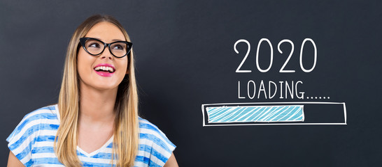 Loading new year 2020 with happy young woman in front of a blackboard