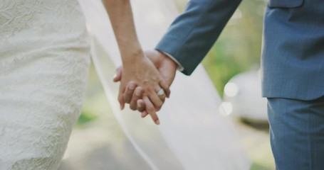 Close up shot of a bride and grooms hands interlocked showing a diamond ring, close up of couple holding hands on their wedding day walking together down the aisle - Powered by Adobe