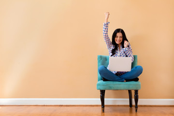 Young woman with a laptop computer with successful pose sitting in a chair