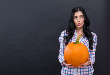 Young woman holding a pumpkin on a black background