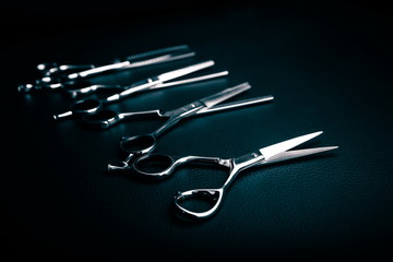 template with hairdressing scissors on black leather background with copy space.