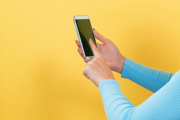 Woman using her smartphone on a yellow background