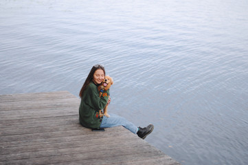 Girl with her dog, English Cocker Spaniel, sitting on the bench near the lake