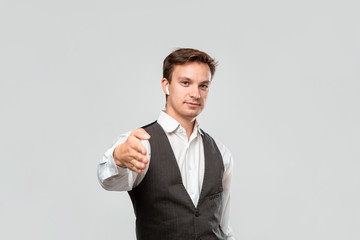 Young businessman in a white shirt and grey vest is ready to shake hands and start successful business project.