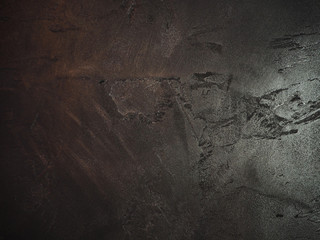 Shiny black metal painted abstract grunge wall in a dark bar, ragged texture background.