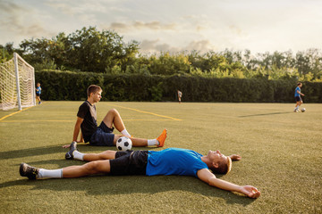 Fototapeta na wymiar Two male soccer players resting on the grass