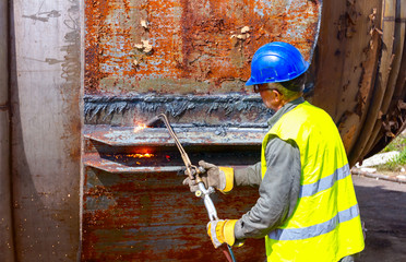 Worker is cutting old metal industrial equipment with acetylene torch