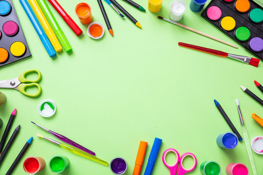 Colorful paints set on green color background, top view